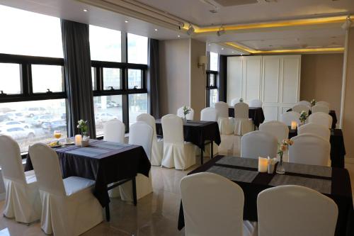 a banquet hall with tables and white chairs at Benikea Hotel Yangsan in Yangsan