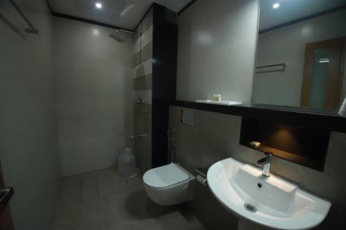 a bathroom with a sink and a toilet and a mirror at GREEN PLANET HOTEL in Mattanūr