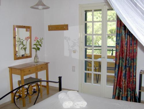 a bedroom with a bed and a table and a window at Aphrodite Studios & Pool in Paleokastritsa