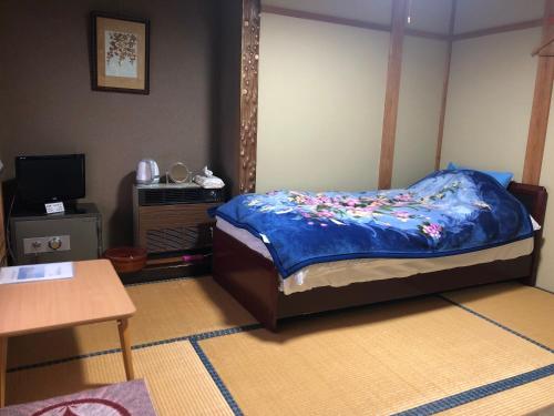 Un dormitorio con una cama con una manta azul con flores. en Tobei, en Nozawa Onsen