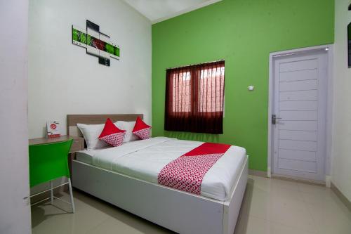 een slaapkamer met groene muren en een bed met rode kussens bij Super OYO 2808 D'residence Syariah in Tegal