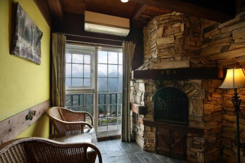 a living room with a stone fireplace and a window at Provence Rose Lodge in Renai