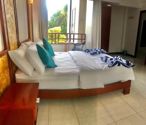 a bed with blue and white pillows in a room at Athens View Hotel in Guraidhoo