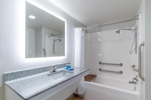 La salle de bains est pourvue d'un lavabo, d'une baignoire et d'un miroir. dans l'établissement Holiday Inn Express Prince Frederick, an IHG Hotel, à Prince Frederick