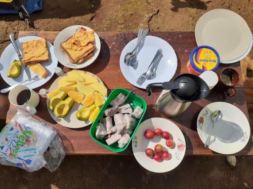een houten tafel met borden met eten erop bij Mai Kilimanjaro Home Stay in Marangu