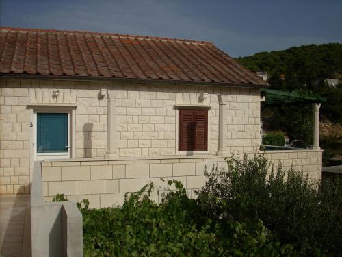 une petite maison en briques blanches avec un toit rouge dans l'établissement Apartments DARIJA & PERO, à Pučišća