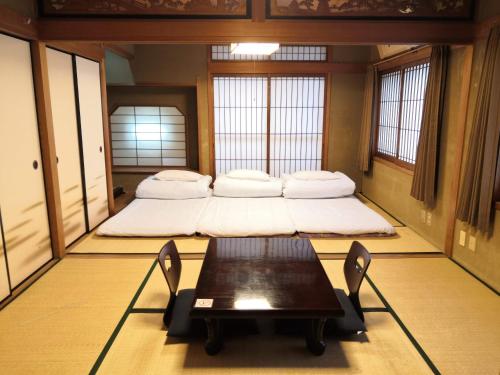 Zimmer mit 2 Betten und einem Tisch in der Unterkunft Tiny GuestHouse Umekoji 梅小路 in Kyoto