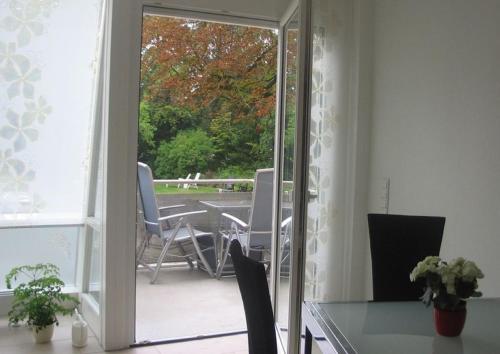 Eine Glastür führt auf eine Terrasse mit einem Tisch und Stühlen. in der Unterkunft Fewo am Kurpark in Bad Sassendorf