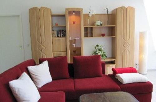 ein Wohnzimmer mit einer roten Couch mit Kissen in der Unterkunft Fewo am Kurpark in Bad Sassendorf
