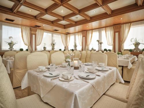 uma sala de jantar com mesas e cadeiras brancas em Rumer Hof em Innsbruck