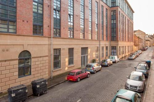Una fila de autos estacionados en una calle al lado de un edificio en Edinburgh Capital Apartments - 49 Elbe Street, en Edimburgo