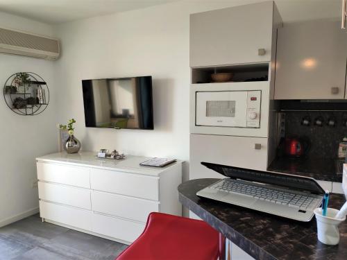 a kitchen with white cabinets and a laptop on a counter at Domaine de La Coudouliere, Vue Mer, Plage, Piscine et Parc in Six-Fours-les-Plages