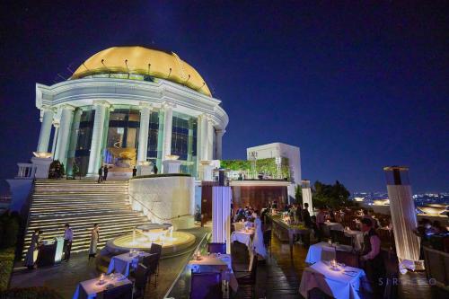 a building with tables and people sitting in front of it at Tower Club at lebua in Bangkok