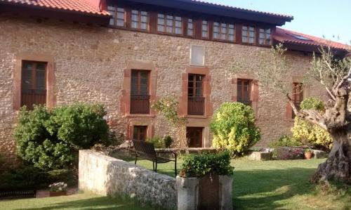 an old stone building with a bench in the yard at Hotel Palacio De La Viñona in Oviedo