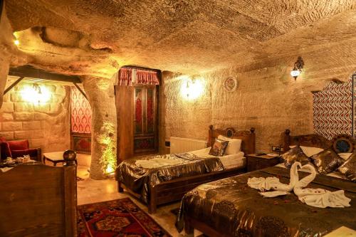 a bedroom with two beds in a stone room at Goreme Palace Cave Suites in Göreme