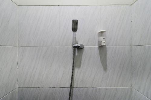 a shower in a tiled wall with a blow dryer at Bantal Guling Pasar Baru in Bandung