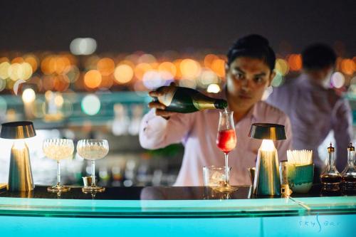 a woman pouring a bottle of wine at a bar at Tower Club at lebua in Bangkok