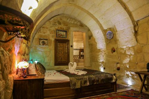 Un dormitorio con una cama en una habitación de piedra. en Goreme Palace Cave Suites, en Göreme
