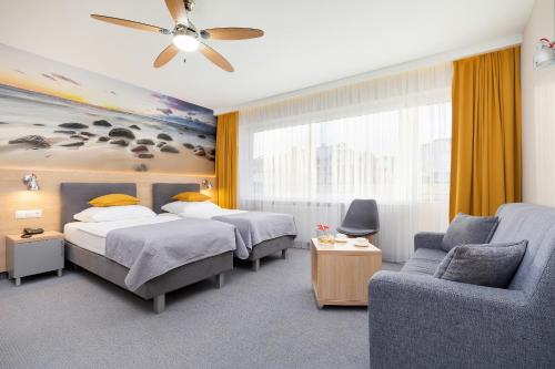 a hotel room with two beds and a couch at Hotel La Siesta & Medical Spa in Jastrzębia Góra