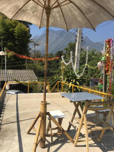 a picnic table with an umbrella next to a bench at Thong Family Homestay Chiangdao in Chiang Dao