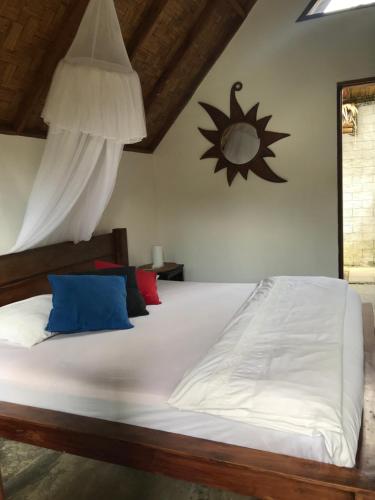 a bedroom with a white bed with blue and red pillows at Villa Paradise in Bukit Lawang