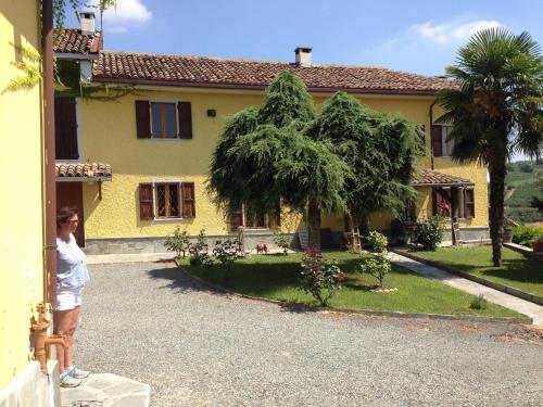 una mujer parada fuera de una casa amarilla en Villa Vinory - Tenuta il Sogno, en San Marzano Oliveto