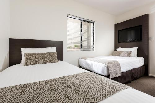 a bedroom with two beds and a flat screen tv at Pier 21 Riverside Apartment Hotel in Fremantle
