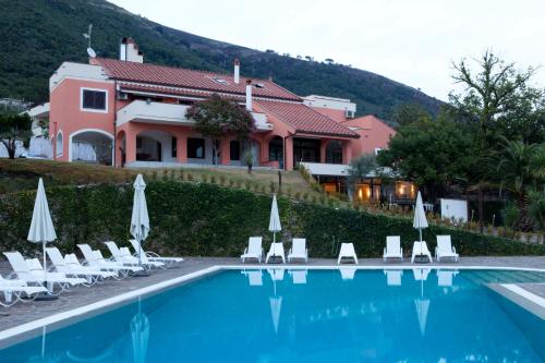 a swimming pool with chairs and umbrellas in front of a house at B&B Villa Setharè in Salerno