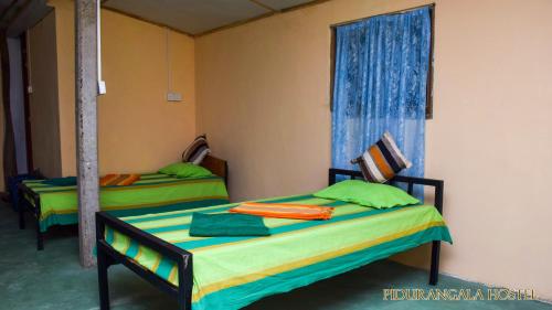 two beds in a room with a window at Pidurangala Hostel in Sigiriya