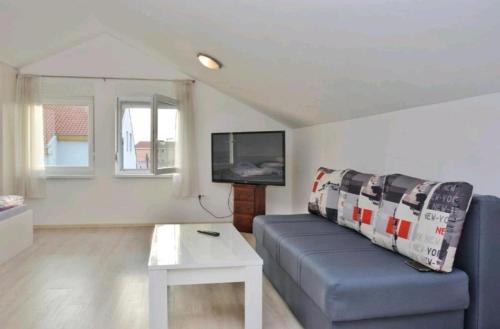 ein Wohnzimmer mit einem blauen Sofa und einem TV in der Unterkunft Urnebes in Zadar