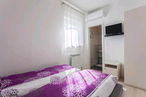 ein Schlafzimmer mit einem lila Bett in einem weißen Zimmer in der Unterkunft Urnebes in Zadar