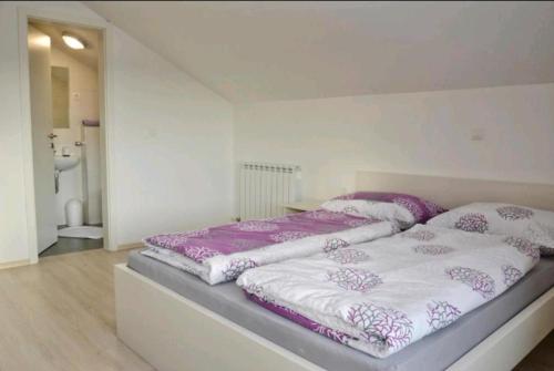 1 Schlafzimmer mit 2 Betten mit lila und weißen Laken in der Unterkunft Urnebes in Zadar