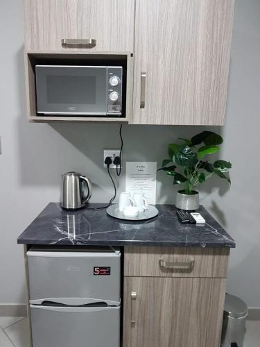 a small kitchen with a counter top with a microwave at A’ La Maison Guesthouse in Kimberley