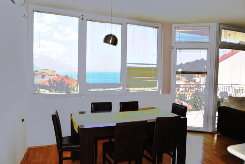 Un comedor con mesa y sillas y ventanas. en Lake View Apartment Ohrid, en Ohrid