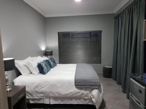 a bedroom with a large white bed with blue pillows at A’ La Maison Guesthouse in Kimberley