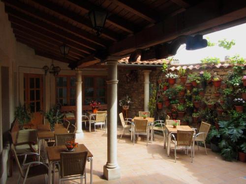 un patio con mesas y sillas y una pared con plantas. en El Portal De Las Arribes, en Aldeadávila de la Ribera