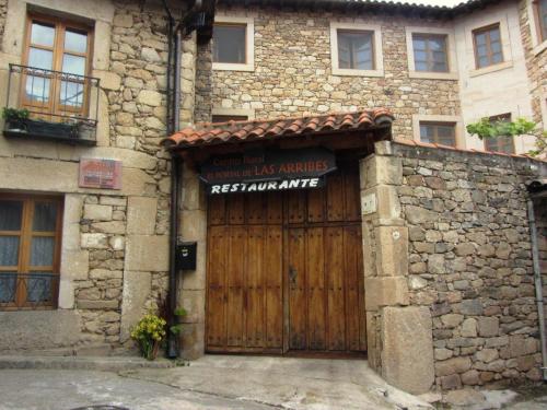 un bâtiment avec une porte en bois et un panneau. dans l'établissement El Portal De Las Arribes, à Aldeadávila de la Ribera