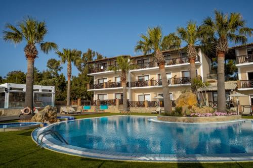 a resort with a large swimming pool and palm trees at Koukis club in Vasilikos