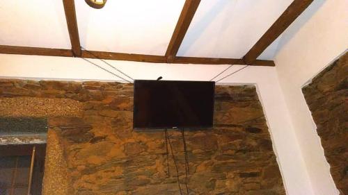 TV de pantalla plana colgada de una pared de piedra en Cozy Xisto, en Mata