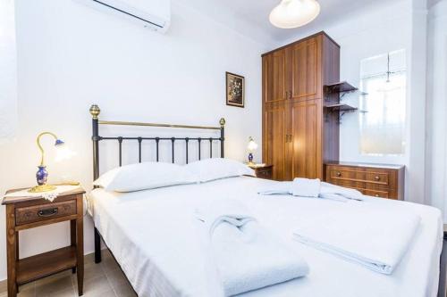 Schlafzimmer mit einem weißen Bett und einem Holzschrank in der Unterkunft Neoclassical apartment with 3 bedrooms in Piraeus in Piräus