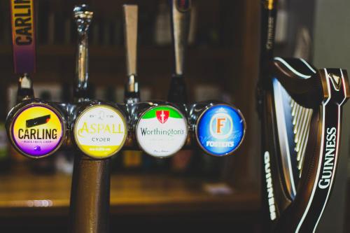 a row of different colored labels on a pole at The Kings Arms in Shap