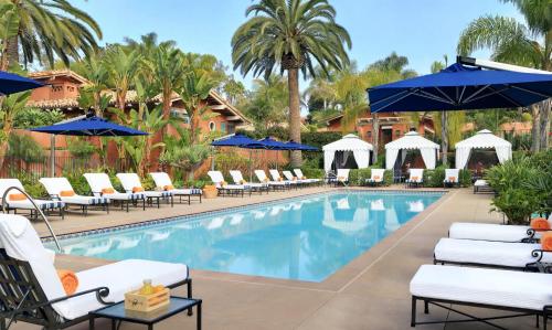 a pool at a resort with lounge chairs and umbrellas at Rancho Valencia Resort and Spa in Rancho Santa Fe