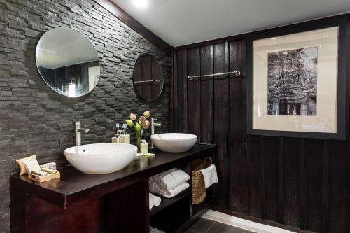 a bathroom with two sinks and a brick wall at Sampeah Retreat Villa in Siem Reap