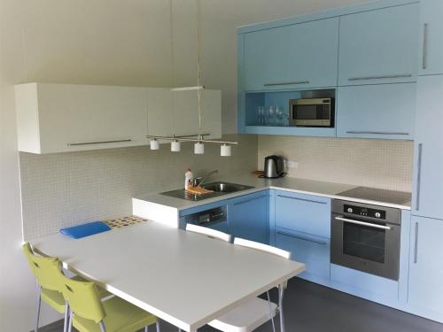 a kitchen with blue cabinets and a white table and chairs at Apartmán v srdci Beskyd - Čeladné in Kunčice pod Ondřejníkem