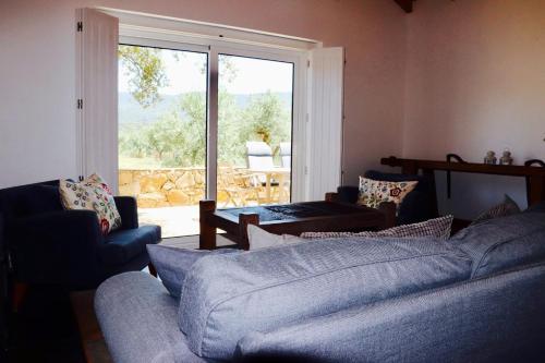 a living room with a couch and a large window at Casa do Sobreiro-Quinta do Briando in Portalegre