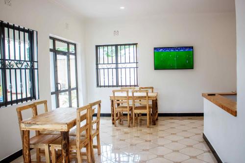 ein Esszimmer mit Tischen und einem TV an der Wand in der Unterkunft Wanyama B&B in Arusha