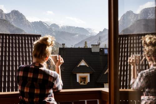 a woman looking out a window at a mountain view at Willa Malinowa in Zakopane