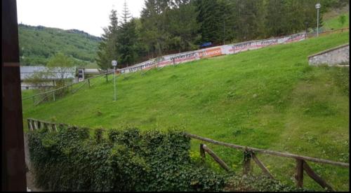 a green field with a fence and a train on it at trilocale sulle piste da sci in Abetone