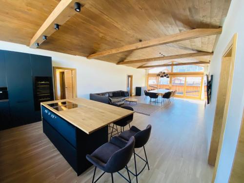 a kitchen and living room with a wooden ceiling at AlpinLodge Flachau in Flachau