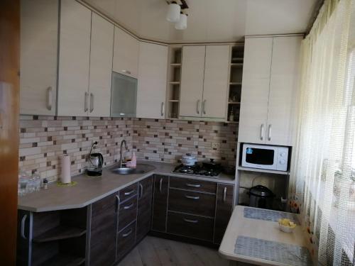 a kitchen with white cabinets and a sink and a microwave at У Ксені in Morshin